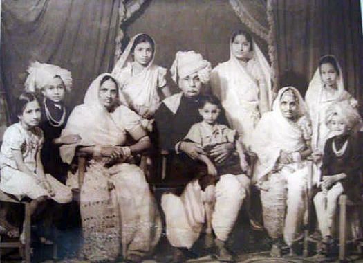 VANAJI'S FAMILY, 1942. Vanaji, wearing the traditional Rajasthani Pheta (turban) is in the middle, holding his 3–year old son. On his left is Santokbai, and on his right is Rambhabai, his other wife. Thirteen year old Diwali is at the back on the left, flanked by her eighteen year old step niece. Santokbai's oldest son, who was quite attached to his stepmother Rambhabai, has his hand on her arm. Vanaji's Family Portrait, 1942
